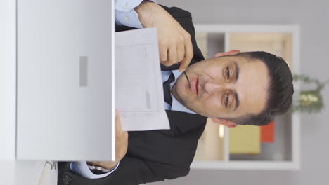 Vertical-video-of-Home-office-worker-man-smiling-at-camera-looking-at-paperwork.